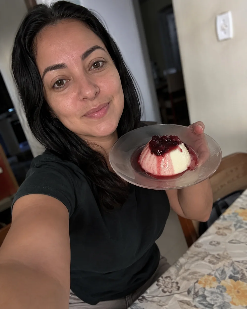 Cliente mostrando uma panna cotta caseira com calda de frutas vermelhas